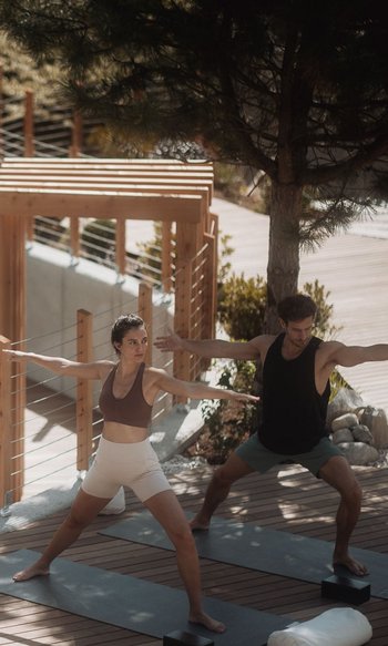 Your hotels in South Tyrol: the home of abundance Two people practicing yoga on wooden deck near pool