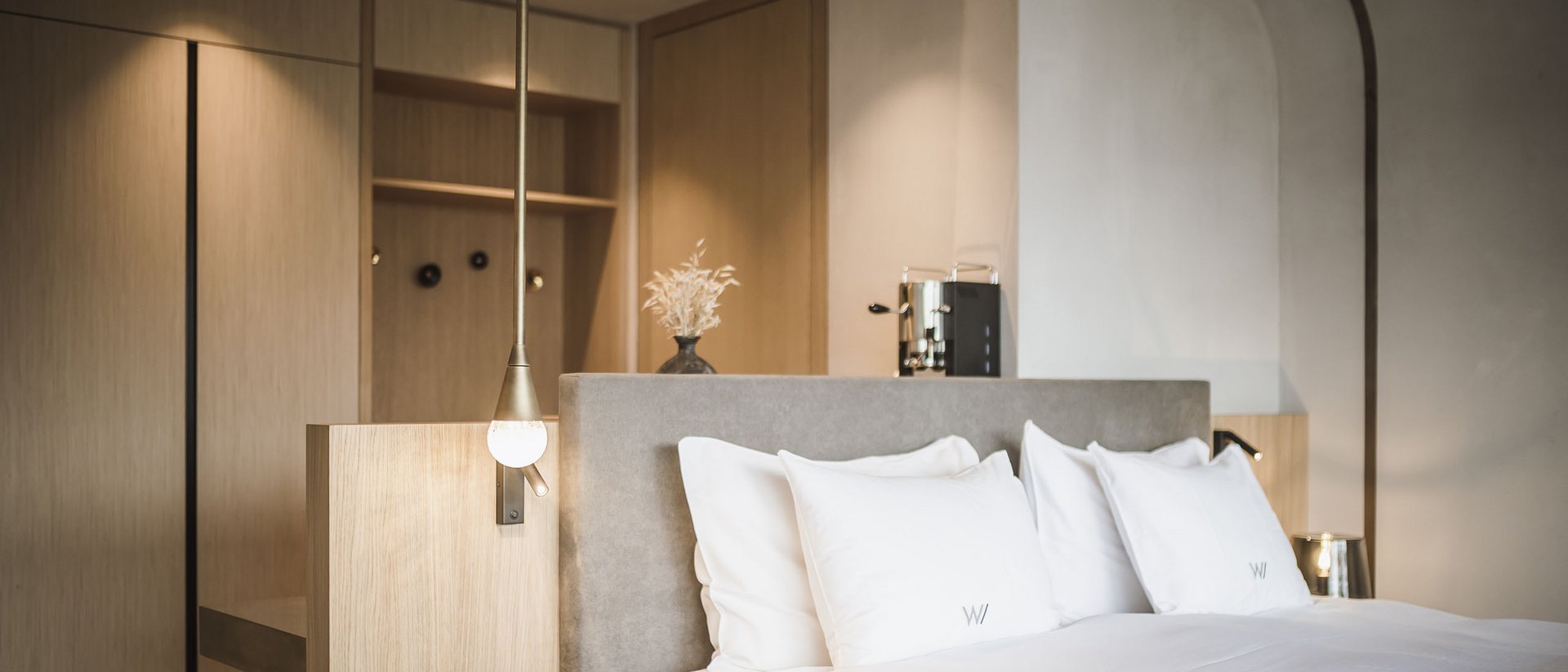 Die Quelle der Erfüllung: Ihr Hotel am Kronplatz Modernes Hotelzimmer mit großem Bett und minimalistischer Einrichtung