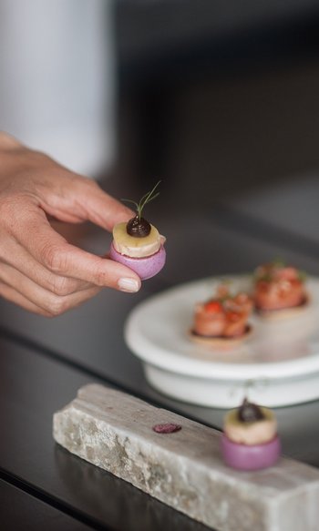Your hotels in South Tyrol: the home of abundance Hand holding a small colorful gourmet bite on a set dining table