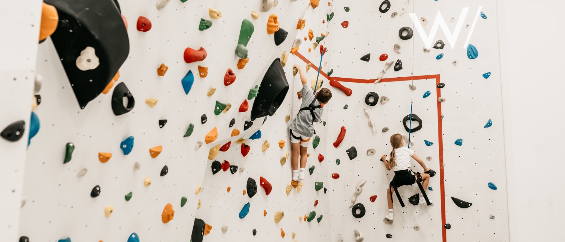 Die Quelle der Erfüllung: Ihr Hotel am Kronplatz Kinder beim Klettern an einer bunten Indoor-Kletterwand
