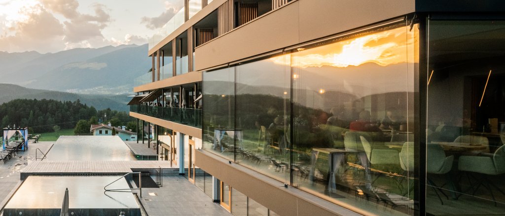 Your hotels in South Tyrol: the home of abundance Modern hotel pool with sun loungers at sunset in a mountain landscape