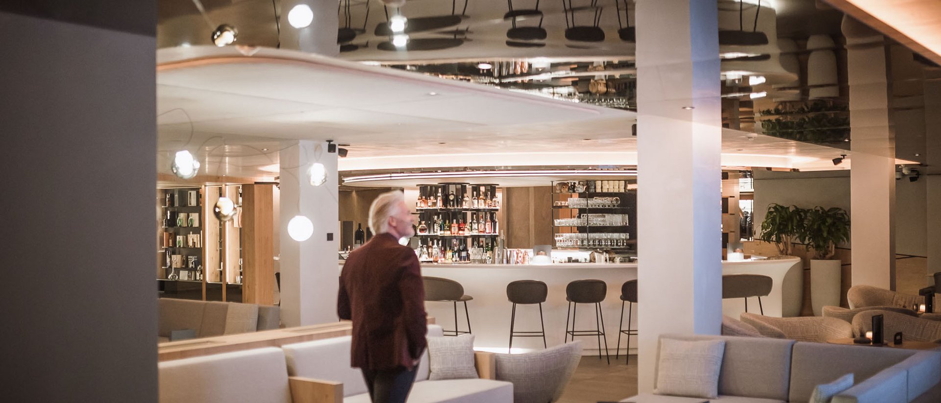 Die Quelle der Erfüllung: Ihr Hotel am Kronplatz Mann in Lounge-Bar mit Sofas und Barhockern