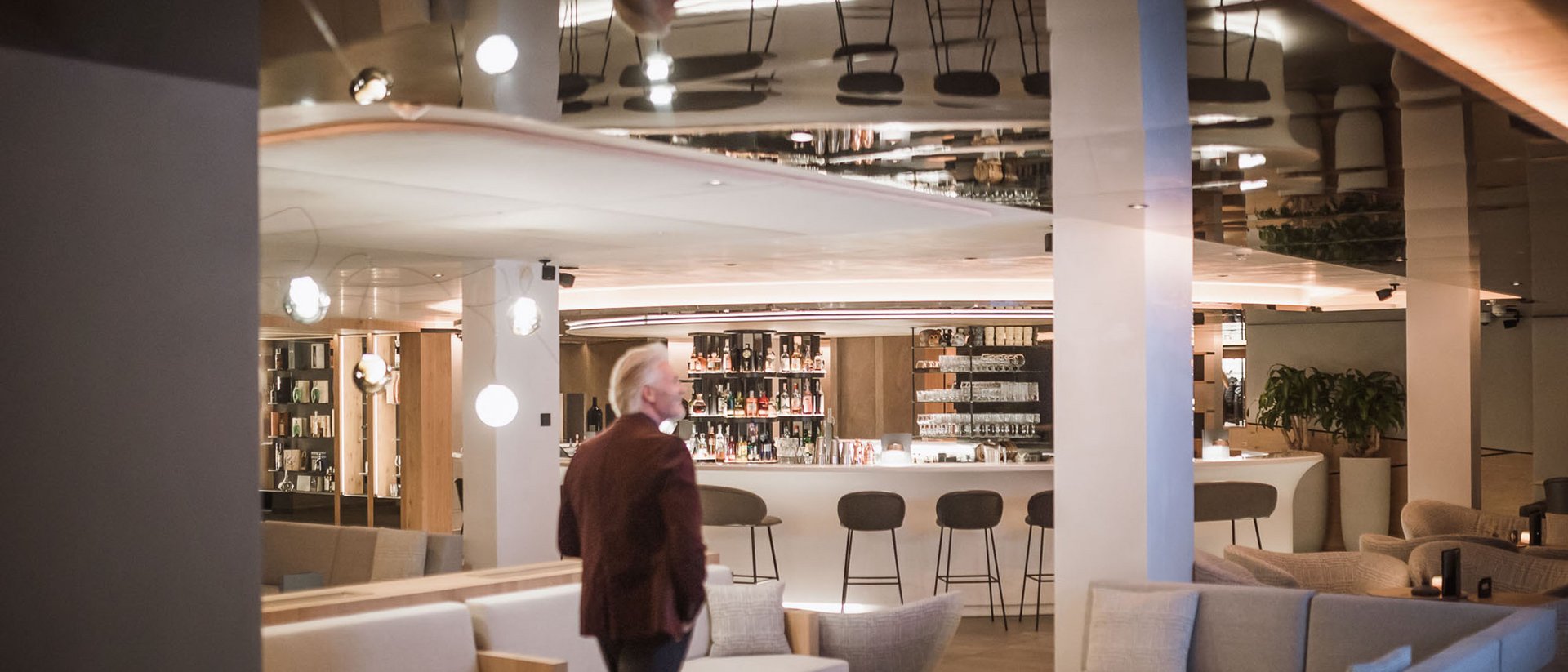 Die Quelle der Erfüllung: Ihr Hotel am Kronplatz Mann in Lounge-Bar mit Sofas und Barhockern