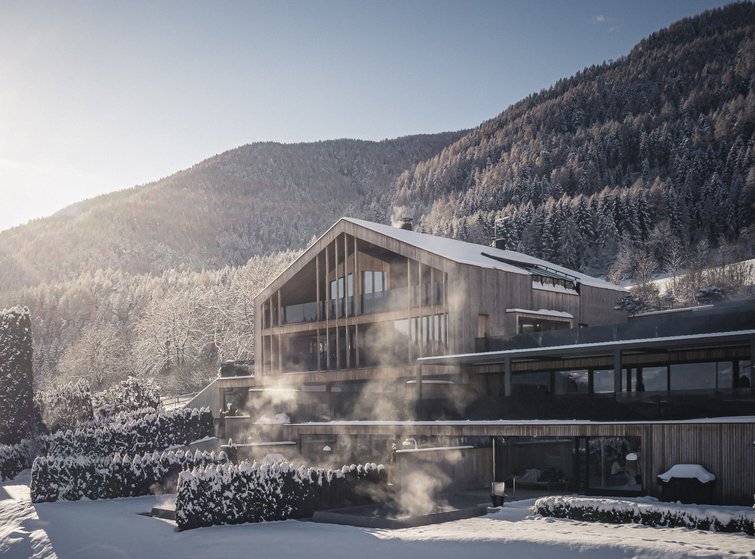 Erfüllender Urlaub in Ihrem Luxus-Chalet in Südtirol Modernes Holzhaus im verschneiten Bergwald bei Sonnenlicht