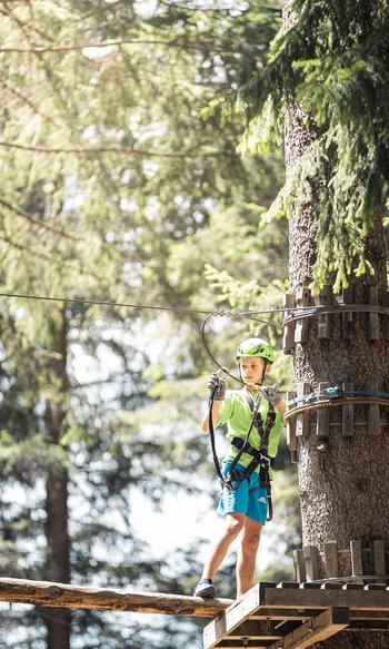 Your hotels in South Tyrol: the home of abundance Boy wearing helmet climbing in an adventure ropes course