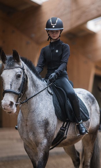 Your hotels in South Tyrol: the home of abundance Young rider on gray horse in indoor arena with second rider blurred in background