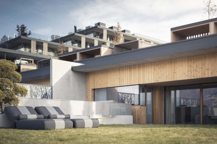 Die Quelle der Erfüllung: Ihr Hotel am Kronplatz Moderne Terrasse mit vier gepolsterten Liegestühlen vor Holzhaus und Wiese