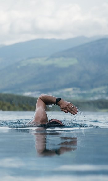 Your hotels in South Tyrol: the home of abundance Person swimming in infinity pool with mountain view