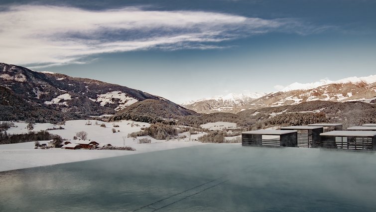 Die Quelle der Erfüllung: Ihr Hotel am Kronplatz Beheizter Außenpool mit Bergblick und schneebedeckten Wiesen im Winter