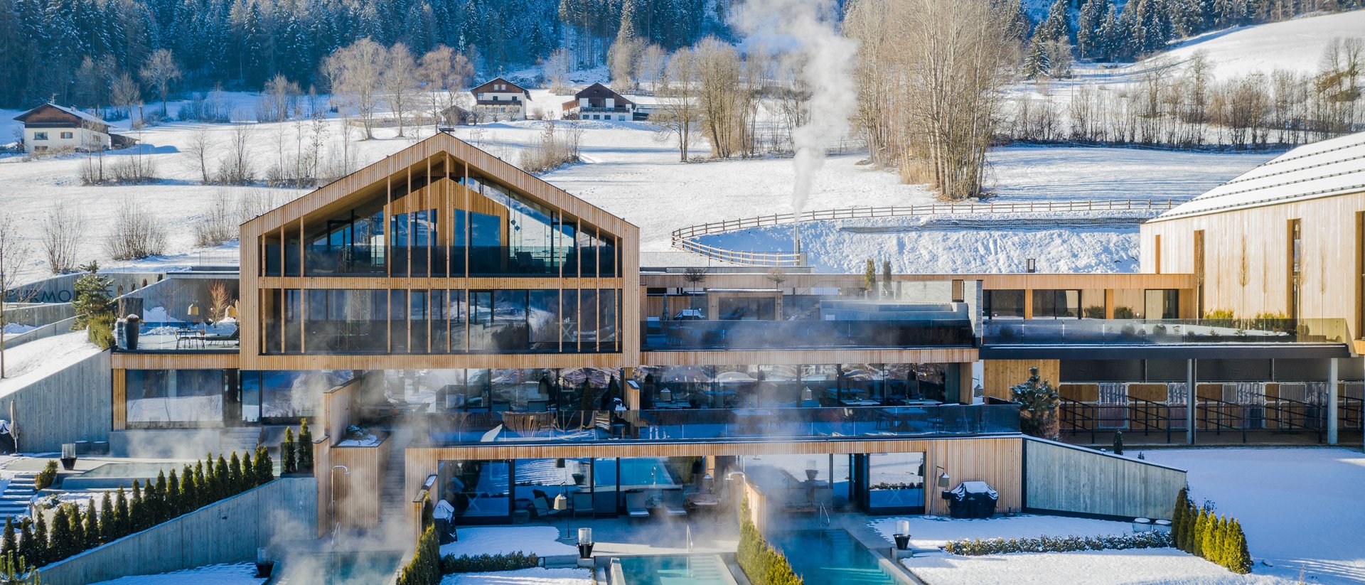 Erfüllender Urlaub in Ihrem Luxus-Chalet in Südtirol Modernes Spa-Hotel mit beheizten Außenpools in verschneiter Berglandschaft