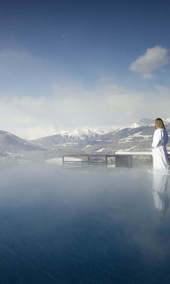Your hotels in South Tyrol: the home of abundance Woman in bathrobe by heated outdoor pool overlooking snowy mountains