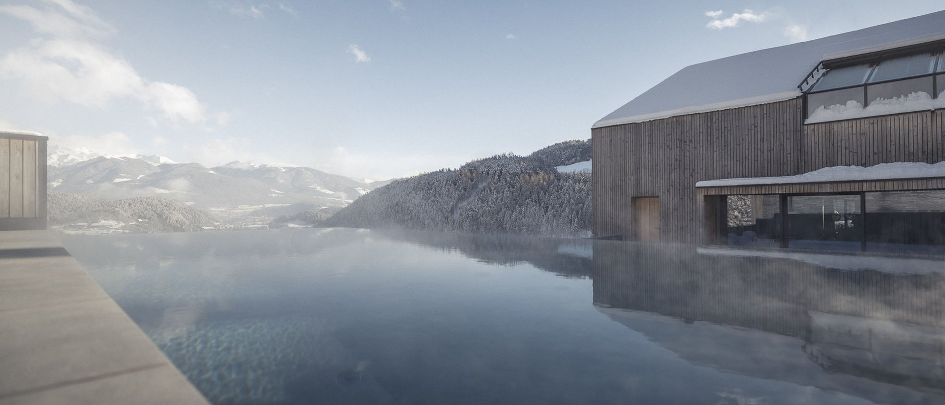 Erfüllender Urlaub in Ihrem Luxus-Chalet in Südtirol Infinity-Pool mit Bergblick und verschneitem Holzhaus unter blauem Himmel