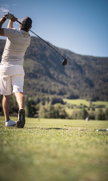 Ihre Hotels in Südtirol: die Heimat der Fülle Mann spielt Golf mit Schlag auf einem Platz vor Bergen
