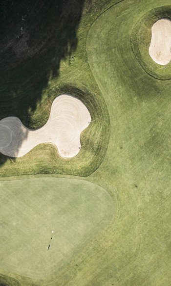 Ihre Hotels in Südtirol: die Heimat der Fülle Drohnenaufnahme eines Golfplatzes mit Sandbunkern und Grünflächen