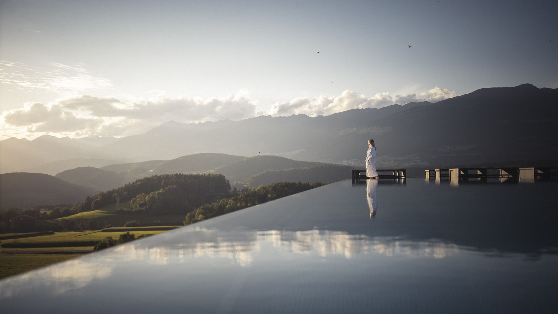 Ihre Hotels in Südtirol: die Heimat der Fülle Person im Bademantel am Infinity-Pool mit Bergblick bei Sonnenuntergang