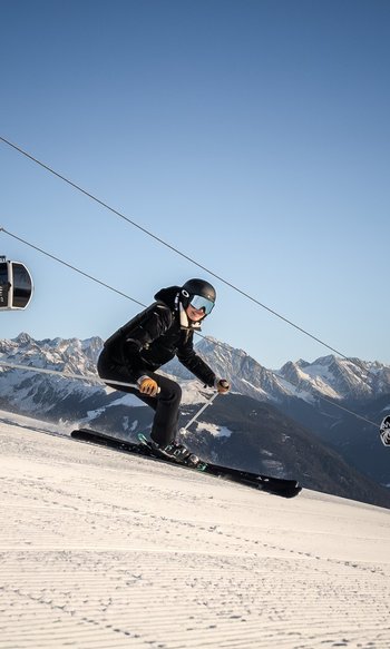 Ihre Hotels in Südtirol: die Heimat der Fülle Skifahrer fährt eine Piste mit Seilbahn und verschneiten Bergen im Hintergrund