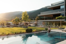 Ihre Hotels in Südtirol: die Heimat der Fülle Mann geht in Pool neben modernem Haus bei Sonnenuntergang in Berglandschaft