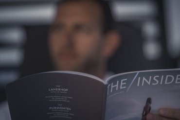 Ihre Hotels in Südtirol: die Heimat der Fülle Person liest Magazin THE INSIDER in unscharfem Hintergrund