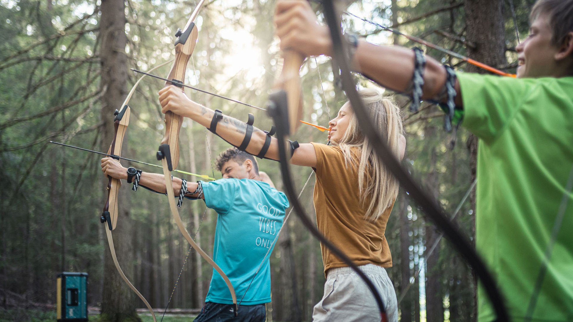 Ihre Hotels in Südtirol: die Heimat der Fülle Drei Personen beim Bogenschießen im Wald