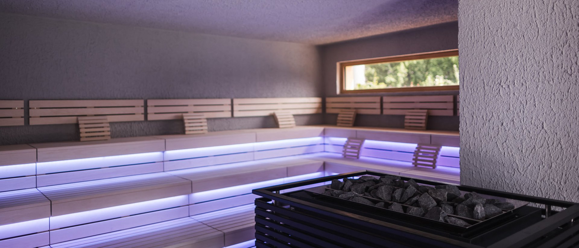 Der Ursprung des Wohlgefühls: Ihr Hotel im Pustertal Moderne Sauna mit Holzbänken und stimmungsvoller Beleuchtung