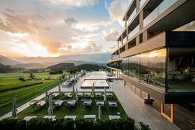 Ihre Hotels in Südtirol: die Heimat der Fülle Moderner Hotelpool mit Sonnenliegen und Bergblick bei Sonnenuntergang