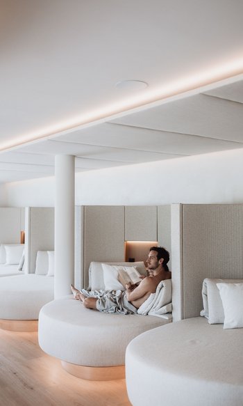 Ihre Hotels in Südtirol: die Heimat der Fülle Mann entspannt auf rundem Sofa in modernem, hellen Ruhebereich