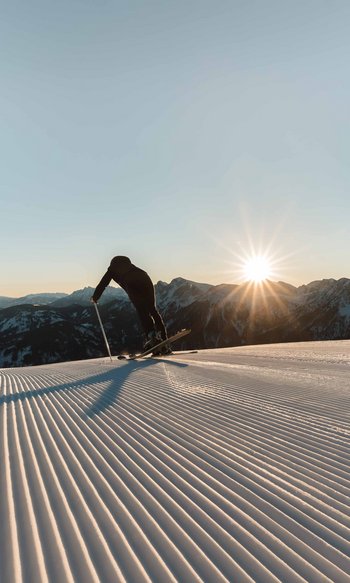Ihre Hotels in Südtirol: die Heimat der Fülle Skifahrer in der Hocke auf frisch präparierter Piste bei Sonnenaufgang in den Bergen