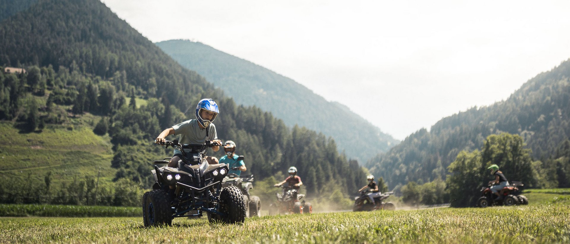 Der Ursprung des Wohlgefühls: Ihr Hotel im Pustertal Kinder fahren Quad in bergiger Landschaft bei sonnigem Wetter