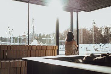 Ihre Hotels in Südtirol: die Heimat der Fülle Frau in Sauna mit Blick auf verschneite Landschaft durch große Fenster