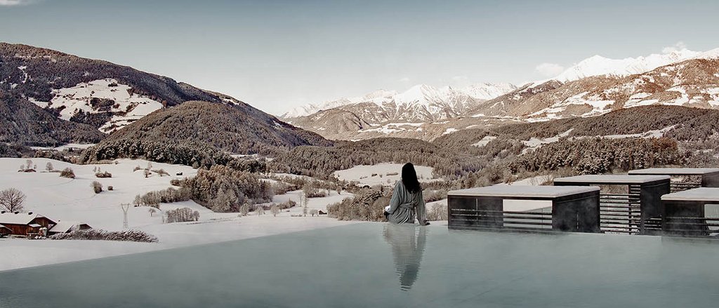 Ihre Hotels in Südtirol: die Heimat der Fülle Person sitzt am Rand eines beheizten Pools mit Blick auf verschneite Berge