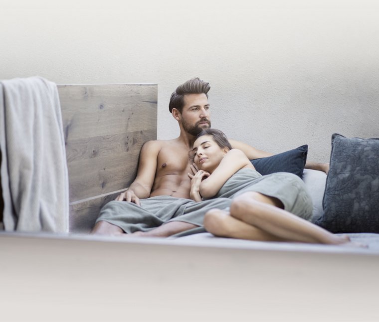 Ihre Hotels in Südtirol: die Heimat der Fülle Paar entspannt zusammen auf einem Bett mit Kissen und Decke