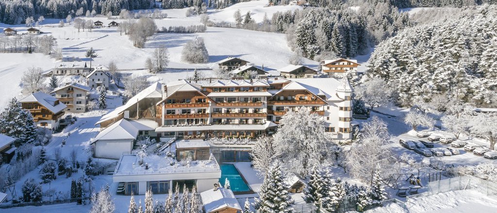 Ihre Hotels in Südtirol: die Heimat der Fülle Hotel in verschneiter Berglandschaft mit umliegenden Bäumen und Feldern