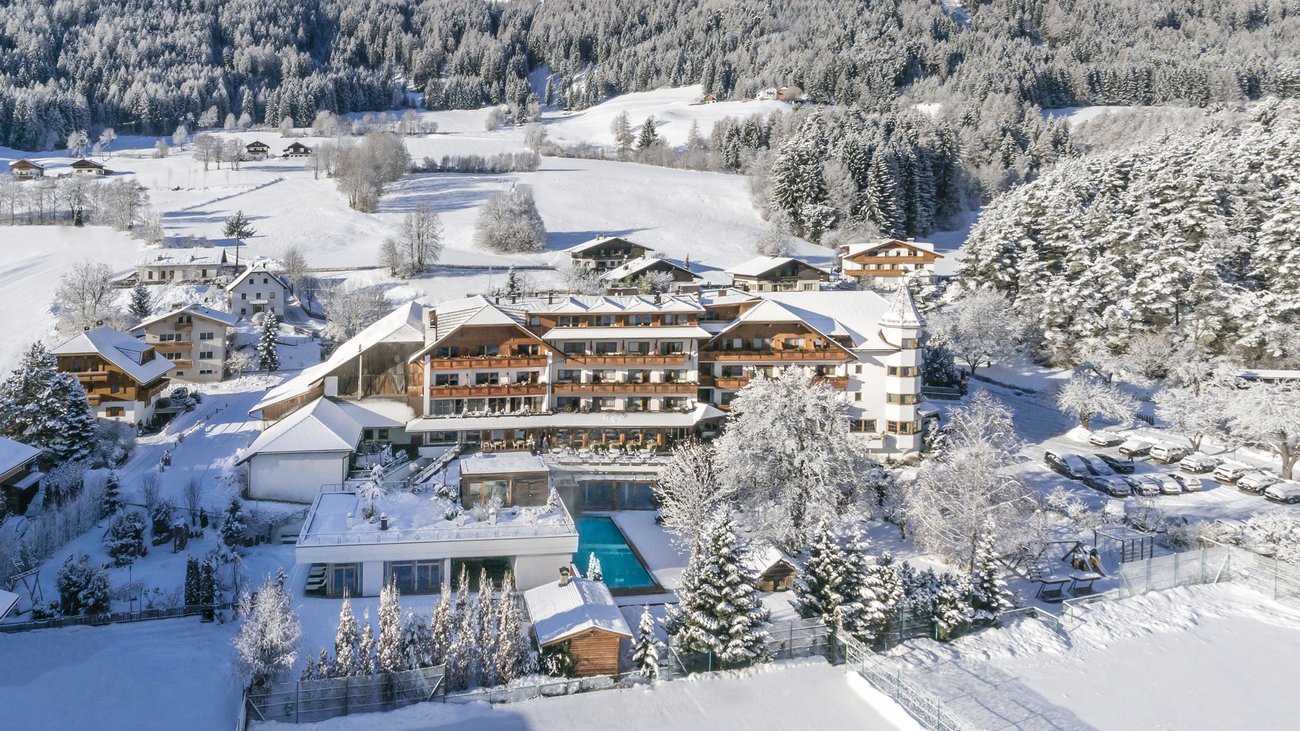 Ihre Hotels in Südtirol: die Heimat der Fülle Hotel in verschneiter Berglandschaft mit umliegenden Bäumen und Feldern