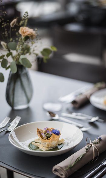 Ihre Hotels in Südtirol: die Heimat der Fülle Fein angerichtete Vorspeise mit essbaren Blüten auf weißem Teller