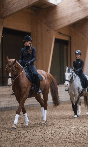 Ihre Hotels in Südtirol: die Heimat der Fülle Reitstunde mit drei Kindern auf Pferden und einem Trainer in einer Halle