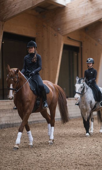 Ihre Hotels in Südtirol: die Heimat der Fülle Reitstunde mit drei Kindern auf Pferden und einem Trainer in einer Halle